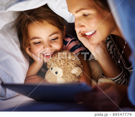 The modern bedtime story. Cropped shot of an attractive young pregnant woman reading her daughter a bedtime story on a tablet. 89547779