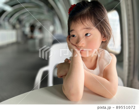 Beautiful little girl with thoughtful look on the table with white space background 89551072