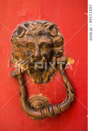 Lion head door knockers on a red door Lion head door knockers on a red door 89551897