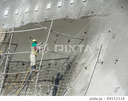 SELANGOR, MALAYSIA -MARCH 4: Construction workers are spraying liquid concrete onto the slope surface to form a retaining wall layer. It acts to prevent erosion on the slope surface. 89552516