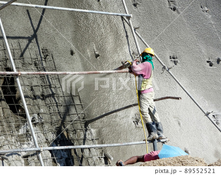 SELANGOR, MALAYSIA -MARCH 4: Construction workers are spraying liquid concrete onto the slope surface to form a retaining wall layer. It acts to prevent erosion on the slope surface. SELANGOR, MALAYSIA -MARCH 4: Construction workers are spraying liquid concrete onto the slope surface to form a retaining wall layer. It acts to prevent erosion on the slope surface. 89552521