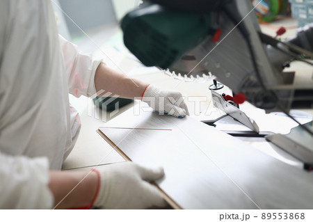Foreman holding wooden plank, put bar under electric saw, going to cut wooden plank 89553868