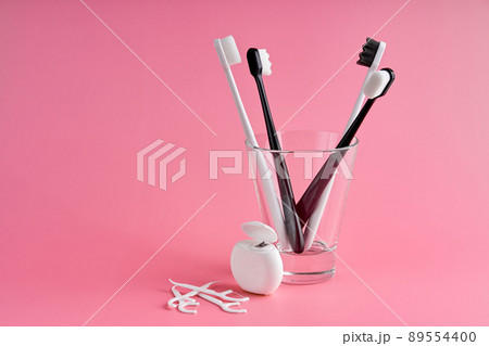 Fashionable toothbrush with soft bristles. Popular toothbrushes. Hygiene trends. Oral hygiene kit. Toothbrushes in glass, floss thread and toothpicks on a pink background Fashionable toothbrush with soft bristles. Popular toothbrushes. Hygiene trends. Oral hygiene kit. Toothbrushes in glass, floss thread and toothpicks on a pink background 89554400