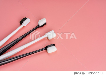 Fashionable toothbrush with soft bristles. Popular toothbrushes. Hygiene trends. Kit of toothbrushes on pink background 89554402