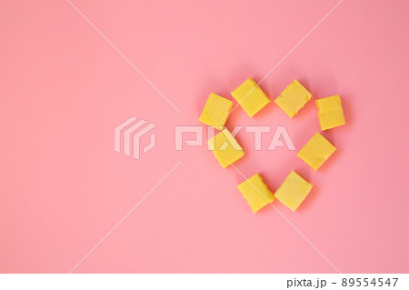 The candy is laid out in the form of a heart. A heart of chewy candies on a pink background. Valentine's Day greeting card. Template for the design. copy space. 89554547