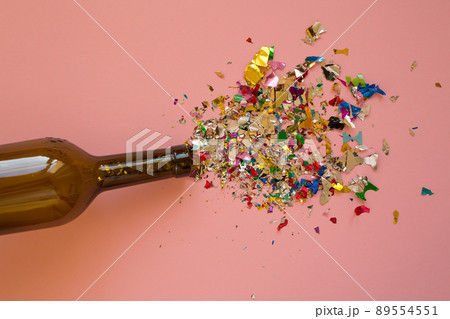 Multicolored sparkling candy on a pink background.Candy spills out of the wine bottle.. Bottle from wine and candy on a pink background Multicolored sparkling candy on a pink background.Candy spills out of the wine bottle.. Bottle from wine and candy on a pink background 89554551