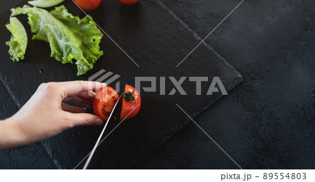 Woman is cutting cherry tomatoes for the salad Woman is cutting cherry tomatoes for the salad 89554803