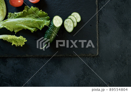 Cucumber and salad leaves on dark slate texture Cucumber and salad leaves on dark slate texture 89554804