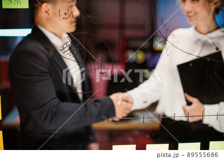 Male and female business colleagues, shaking hands after finishing up the meeting in modern office Male and female business colleagues, shaking hands after finishing up the meeting in modern office 89555686