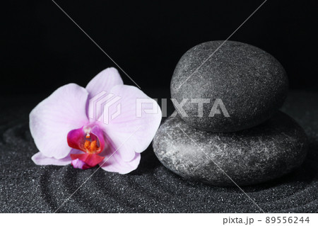 Spa stones and orchid flower on black sand with beautiful pattern. Zen concept 89556244
