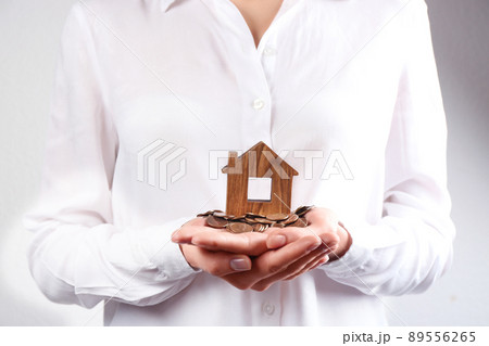 Woman holding house model and coins, closeup 89556265