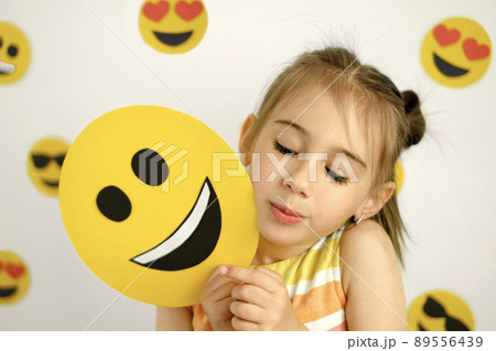 Person looks curiously at the happy emoticon. A diverse emotional state. World emoji day Person looks curiously at the happy emoticon. A diverse emotional state. World emoji day 89556439