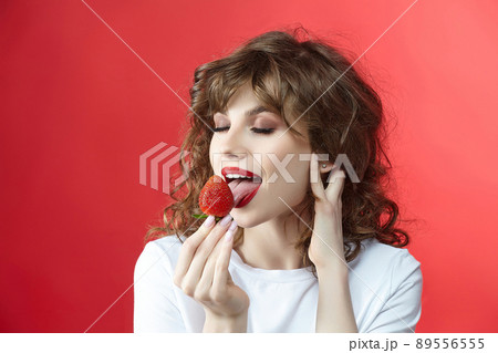 attractive girl with a smile holds a strawberry berry in her hands. 89556555