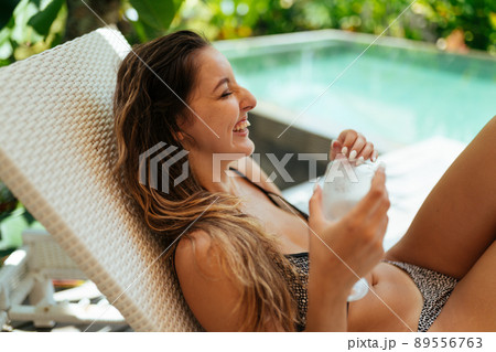 by the pool in Shizong, a girl in a swimsuit laughs holding a glass by the pool in Shizong, a girl in a swimsuit laughs holding a glass 89556763
