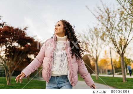 running through the autumn park girl with curly long hair smiles happily 89556893