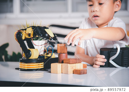 Happy Asian little kid boy using remote control playing robotic machine arm for pick up wood block 89557972