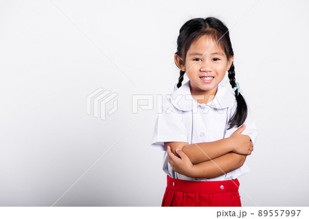 Asian toddler smile happy wearing student thai uniform red skirt stand with arms folded 89557997