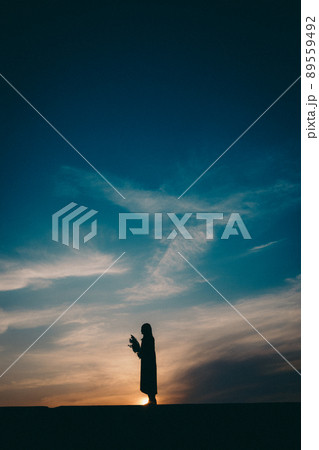 女性のシルエットと美しい夕焼け空 89559492