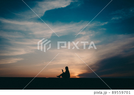 女性のシルエットと美しい夕焼け空 89559701