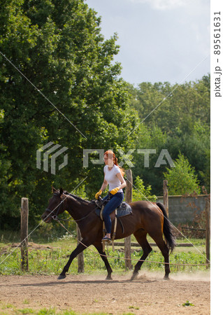 A redhead woman riding a horse on a leash 89561631