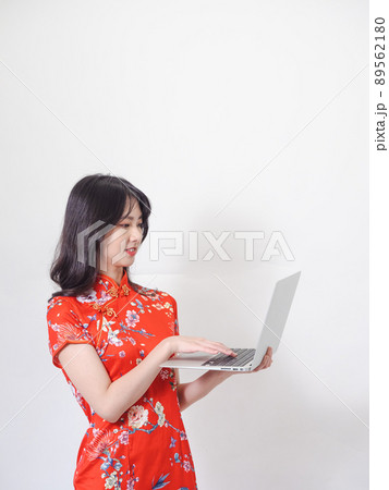 Portrait of a young asian woman in traditional cheongsam qipao dress using laptop on white background. Portrait of a young asian woman in traditional cheongsam qipao dress using laptop on white background. 89562180