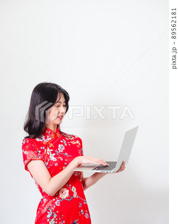 Portrait of a young asian woman in traditional cheongsam qipao dress using laptop on white background. 89562181