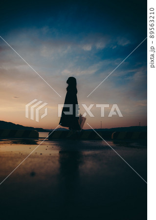 傘を持った女性のシルエットと美しい夕焼け空 89563210