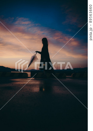 傘を持った女性のシルエットと美しい夕焼け空 89563660
