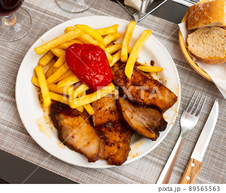 Roasted pork loin slices with fried potatoes and baked red pepper 89565563