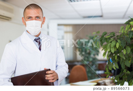 Portrait of male doctor in protective mask in the office of modern clinic Portrait of male doctor in protective mask in the office of modern clinic 89566073
