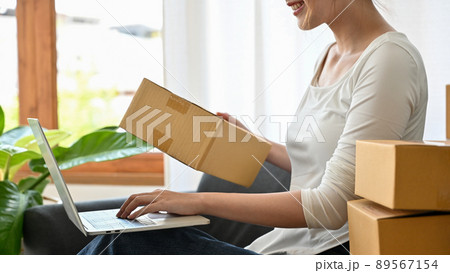 Cropped image, woman using laptop computer and preparing her shipping package Cropped image, woman using laptop computer and preparing her shipping package 89567154