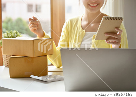 Female online seller checking sale orders on tablet and preparing the product to ship 89567165