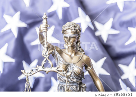 The statue of justice Themis or Iustitia, the goddess of justice blindfolded against a flag of the United States of America, as a legal concept. The statue of justice Themis or Iustitia, the goddess of justice blindfolded against a flag of the United States of America, as a legal concept. 89568351