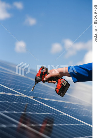Close up view of engineer working with electric screwdriver drill installing solar panel to metal base Close up view of engineer working with electric screwdriver drill installing solar panel to metal base 89569768