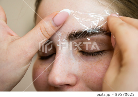 The master uses a plastic film during lamination of the eyebrows. The master uses a plastic film during lamination of the eyebrows. 89570625