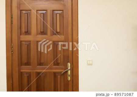 Wooden door on white wall close up Wooden door on white wall close up 89571087