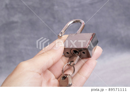 Metal padlock and keys in hand on gray background 89571111