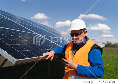 Man in hard hat using smartphone on the background of solar panels 89571639