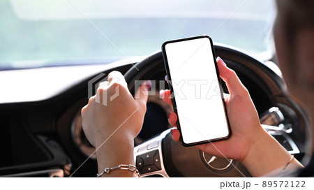 Close up on driver using smart phone for communication while driving car. 89572122