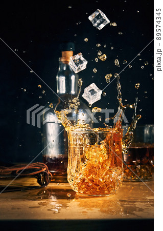 ice falls into a glass of cognac ice falls into a glass of cognac 89574345