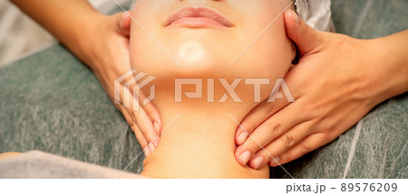 Facial massage. Hands of a masseur massaging neck of a young caucasian woman in a spa salon, the concept of health massage 89576209