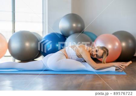 Pretty girl doing twine on yoga mat. .Flexible girl stretching indoors 89576722