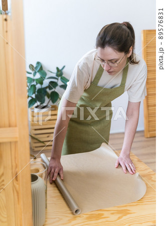 A florist in apron unwraps a craft wrapping paper. Flower and gift shop. Female Seller 89576831