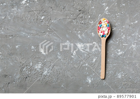 Vitamin capsules in a wooden spoon on a colored background. Pills served as a healthy meal. Drugs, pharmacy, medicine or medical healthycare concept Vitamin capsules in a wooden spoon on a colored background. Pills served as a healthy meal. Drugs, pharmacy, medicine or medical healthycare concept 89577901