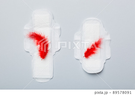 Women hygiene products or Sanitary pad with red feather on colored background. Pastel color. Closeup. Empty place for text. Female daily hygiene 89578091