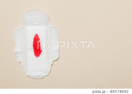 Women hygiene products or Sanitary pad with red feather on colored background. Pastel color. Closeup. Empty place for text. Female daily hygiene Women hygiene products or Sanitary pad with red feather on colored background. Pastel color. Closeup. Empty place for text. Female daily hygiene 89578092