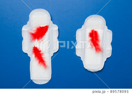 Women hygiene products or Sanitary pad with red feather on colored background. Pastel color. Closeup. Empty place for text. Female daily hygiene Women hygiene products or Sanitary pad with red feather on colored background. Pastel color. Closeup. Empty place for text. Female daily hygiene 89578093