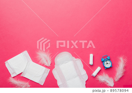 Ringing alarm clock with sanitary female tampons and menstrual sanitary pads. Medical concept of woman critical days and menstruation. Female daily hygiene. Copy space Ringing alarm clock with sanitary female tampons and menstrual sanitary pads. Medical concept of woman critical days and menstruation. Female daily hygiene. Copy space 89578094