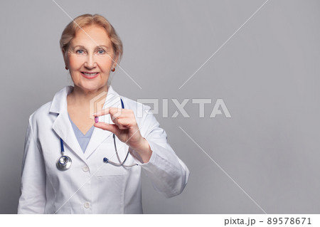 Portrait of senior doctor with medical pill remedy on grey background 89578671
