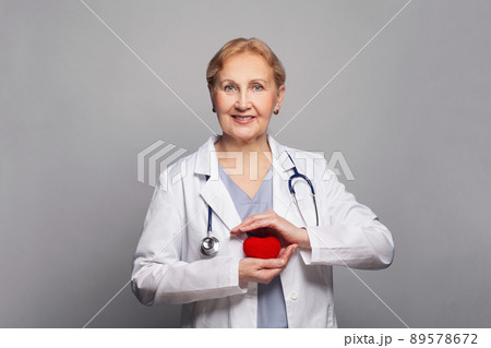 Smiling mature doctor with red heart in her hands Smiling mature doctor with red heart in her hands 89578672